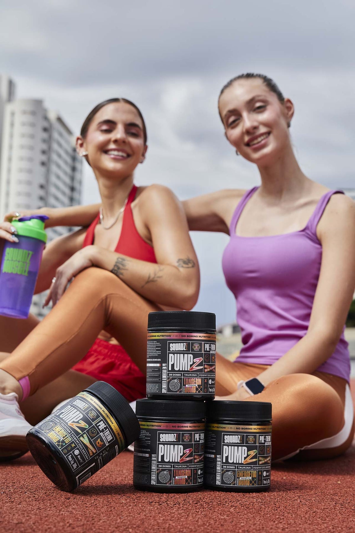 Duas mulheres sentadas ao ar livre com potes de PUMP-Z pré-treino à frente