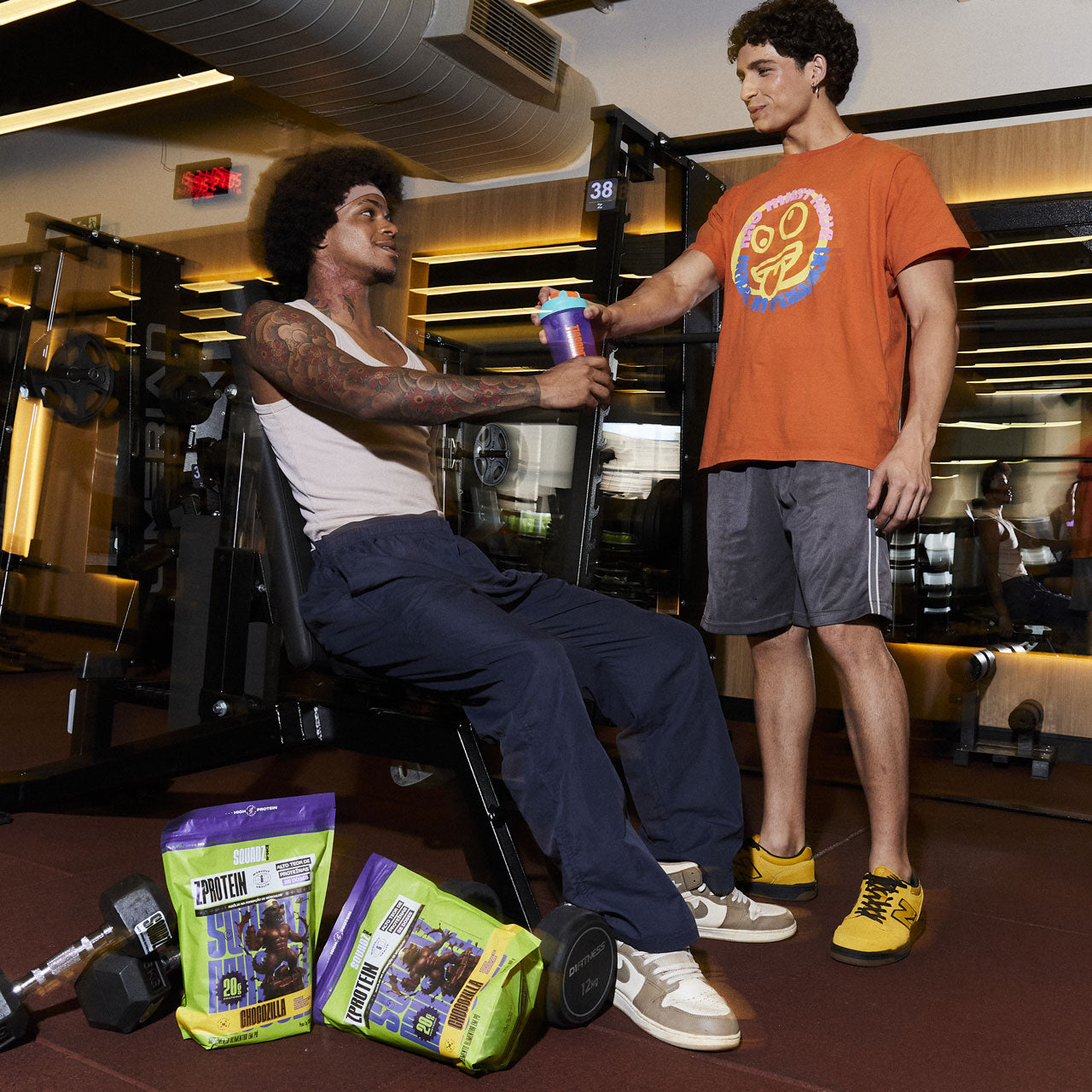 Dois homens na academia com sacos de ZPROTEIN Chocozilla