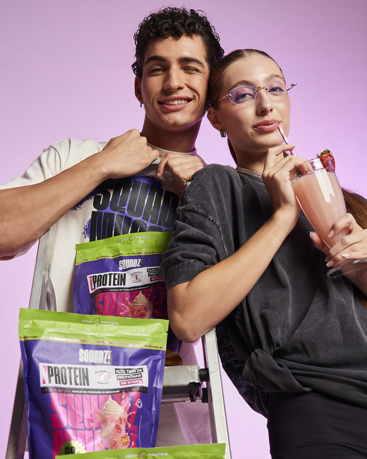 Casal segurando copos de shake e sacos de ZPROTEIN Milkshake de Morango