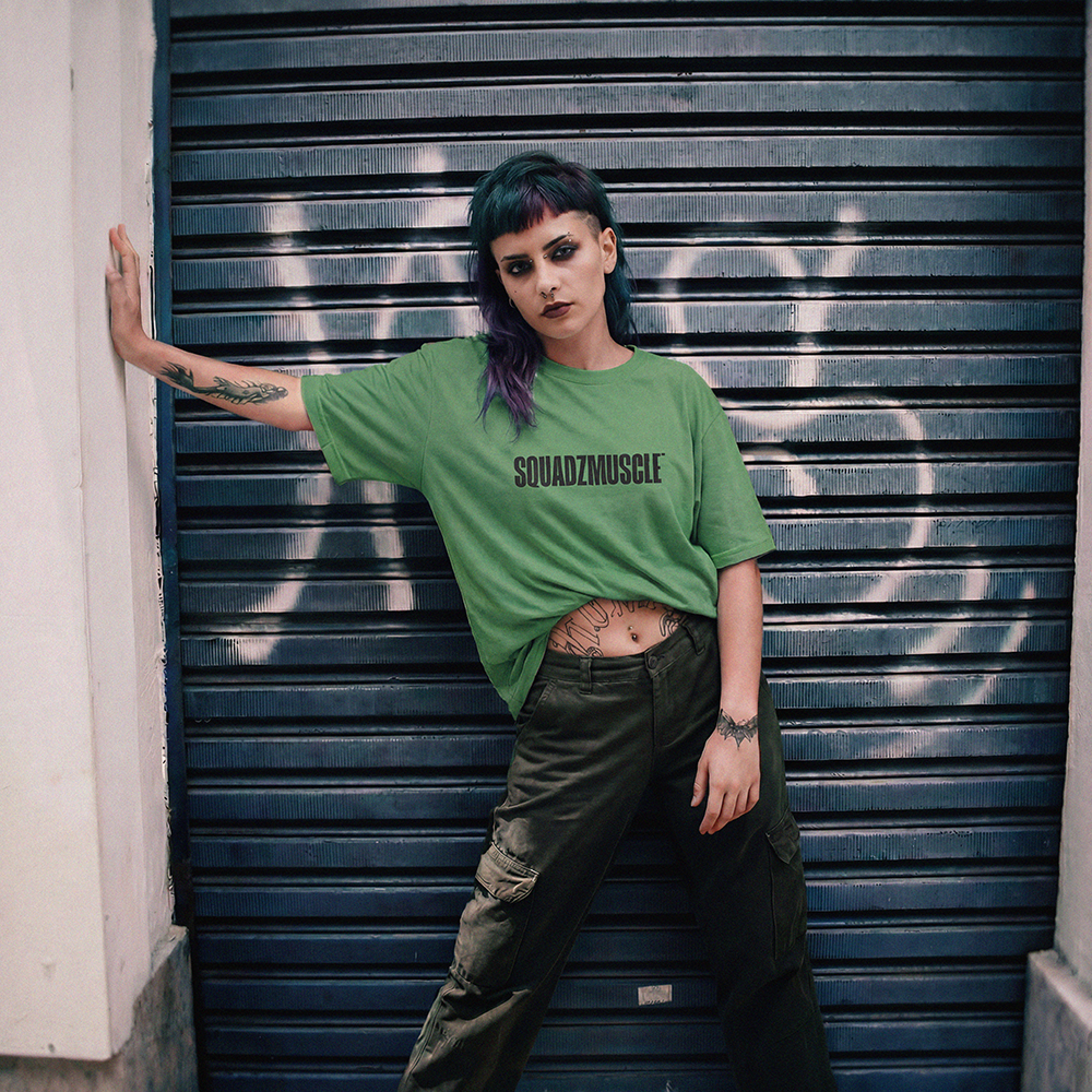 Camiseta Oversized Verde SQUADZ MUSCLE — Mulher em frente a porta de aco