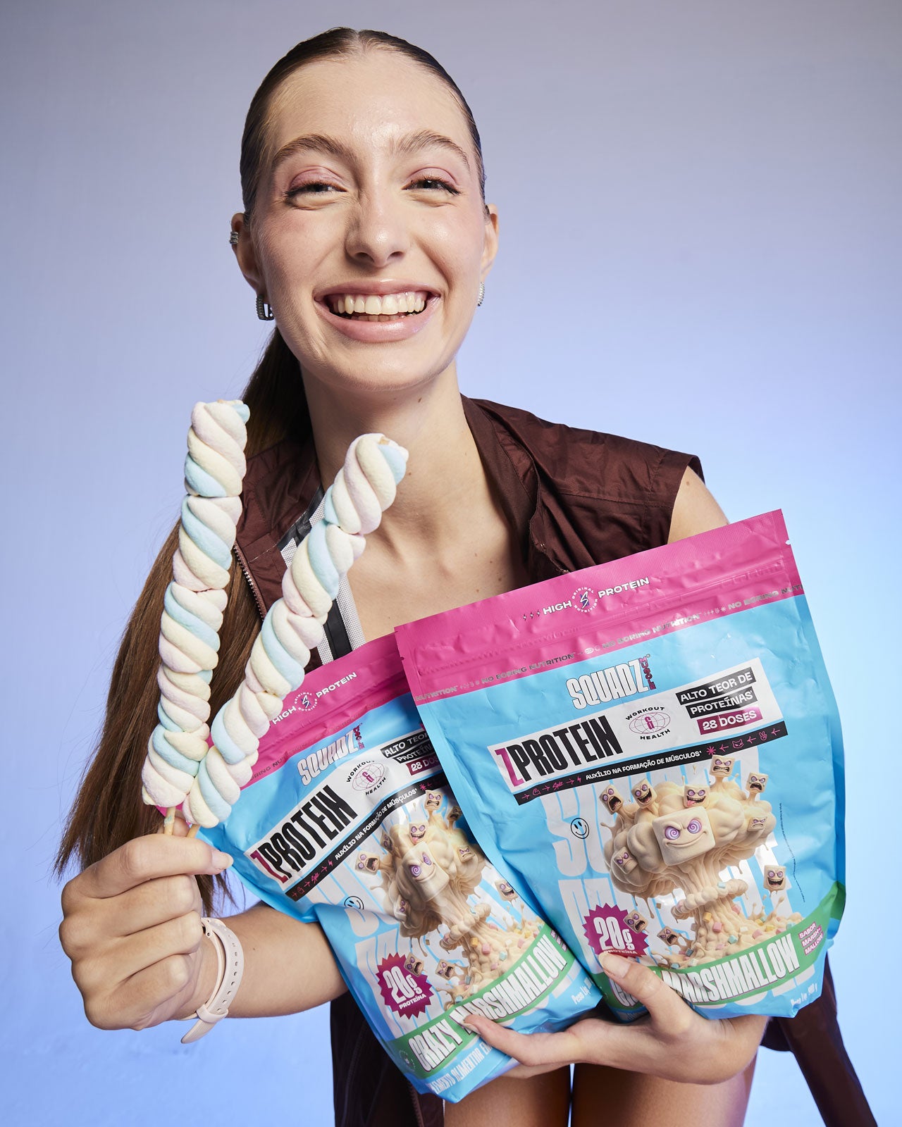 Mulher sorrindo com um marshmallow na mão e sacos de ZPROTEIN Marshmallow