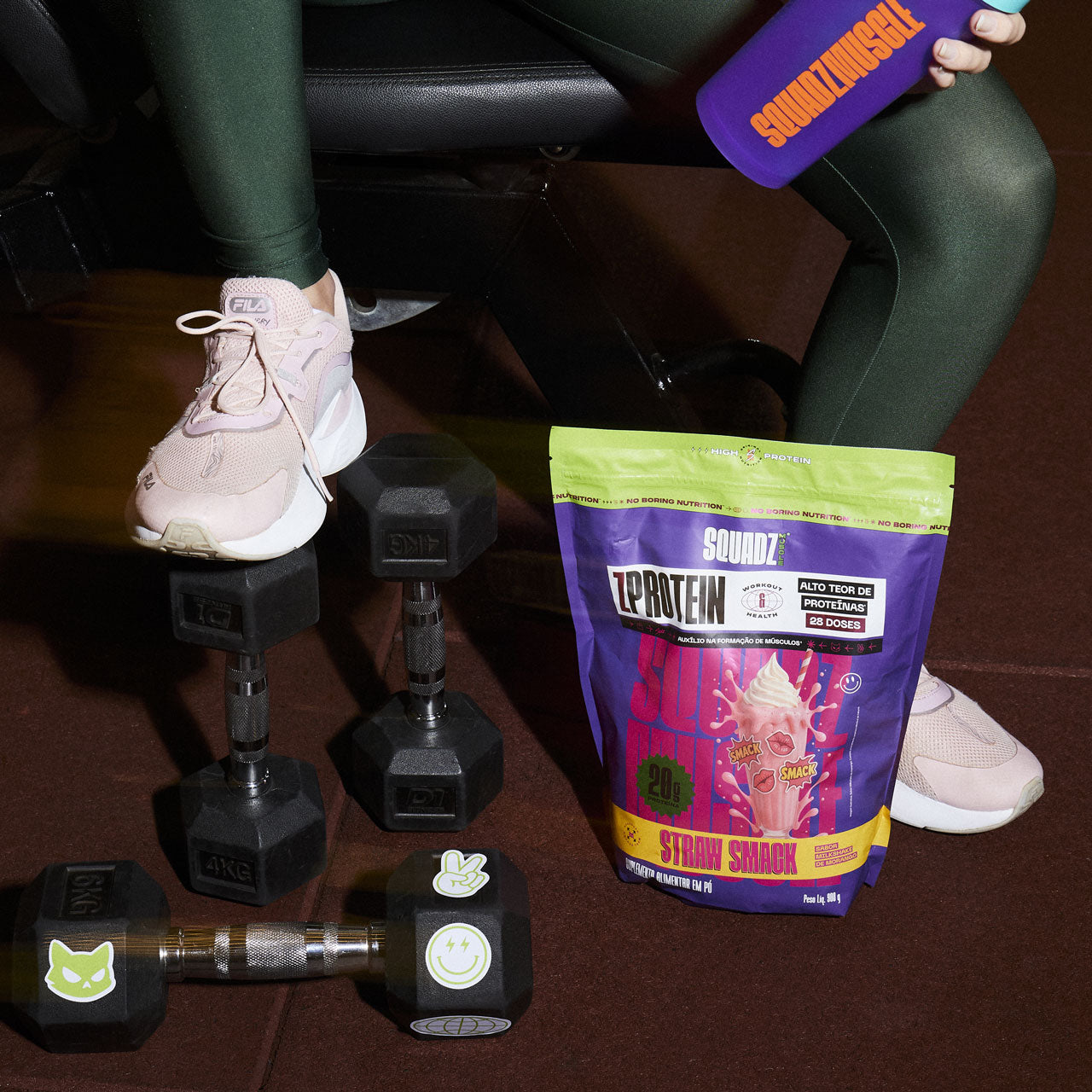 Saco de ZPROTEIN Milkshake de Morango na academia, ao lado de halteres
